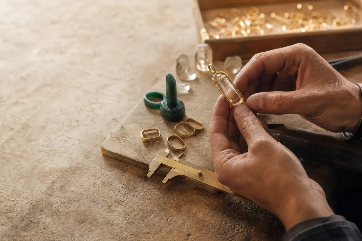 Jewelry maker inspecting a crystal pendant in a workshop